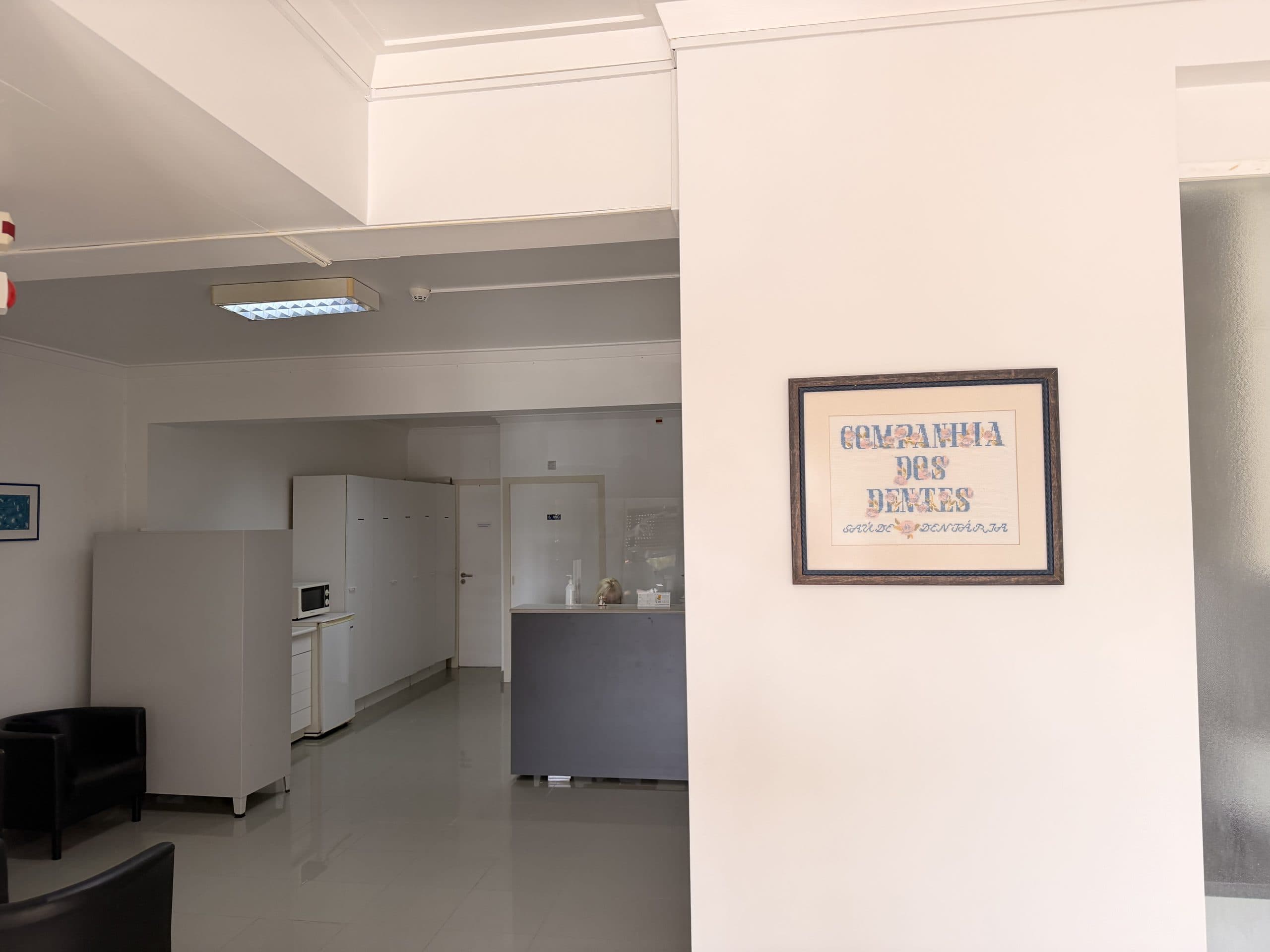 Receção da Companhia dos Dentes, com o quadro em ponto de cruz do nome da clínica